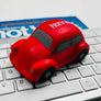 Red toy car on a computer keyboard with a magazine in the background