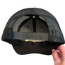 Black mesh cap held by a hand against a black background